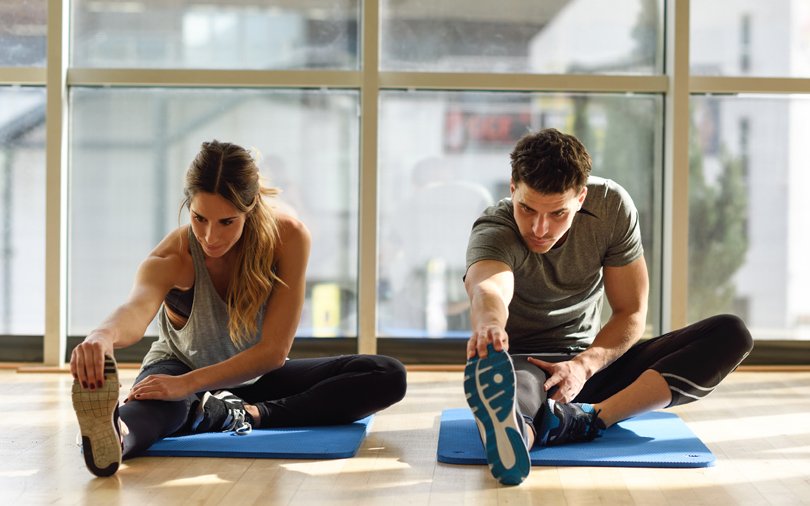 Couple stretching on mats demonstrating flexible fitness coaching in Elmbridge.